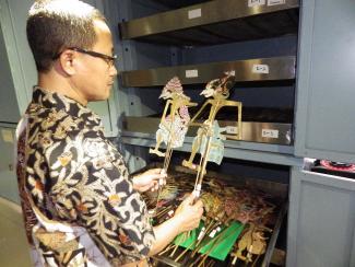 A man examines two puppets in a museum collection