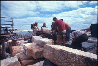 A group of people moving blocks from the Batavia portico along a jetty