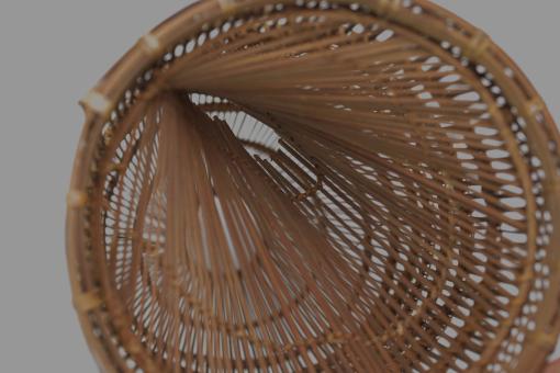Detail of a tall, slender bamboo Fish Trap (Bubu) with a conical shape and woven grid pattern.