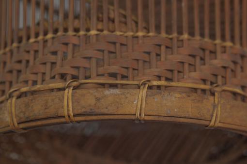 Detail of a tall, slender bamboo Fish Trap (Bubu) with a conical shape and woven grid pattern.