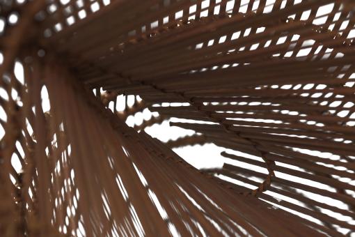Detail of a tall, slender bamboo Fish Trap (Bubu) with a conical shape and woven grid pattern.