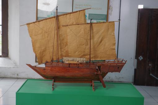 Image depicting a Padewakang Boat Miniature, a small wooden sail boat on display