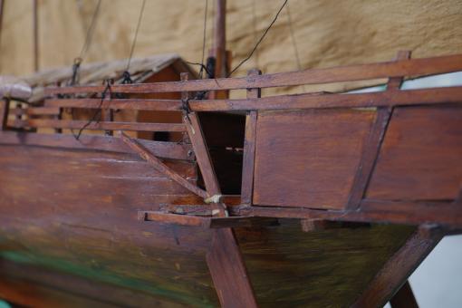 Image depicting a Padewakang Boat Miniature, a small wooden sail boat on display