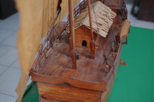Image depicting a Padewakang Boat Miniature, a small wooden sail boat on display