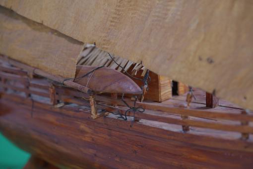 Image depicting a Padewakang Boat Miniature, a small wooden sail boat on display