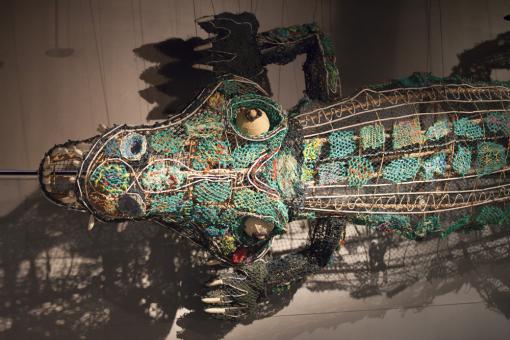 Suspended colourful crocodile sculpture made from nets and metal wires.
