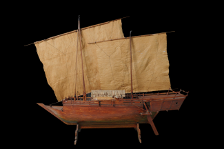 A miniature boat with sails displayed on a black background