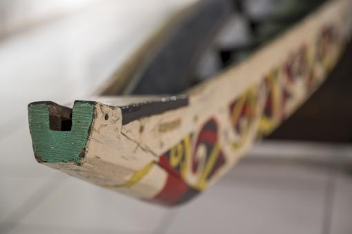 Detail of a Dayak Long Boat, showing the green painted prow and yellow, black and red designs on the sides of the boat.