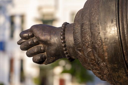 Detail of a cannon, in the shape of a human hand and wrist wearing a bracelet.